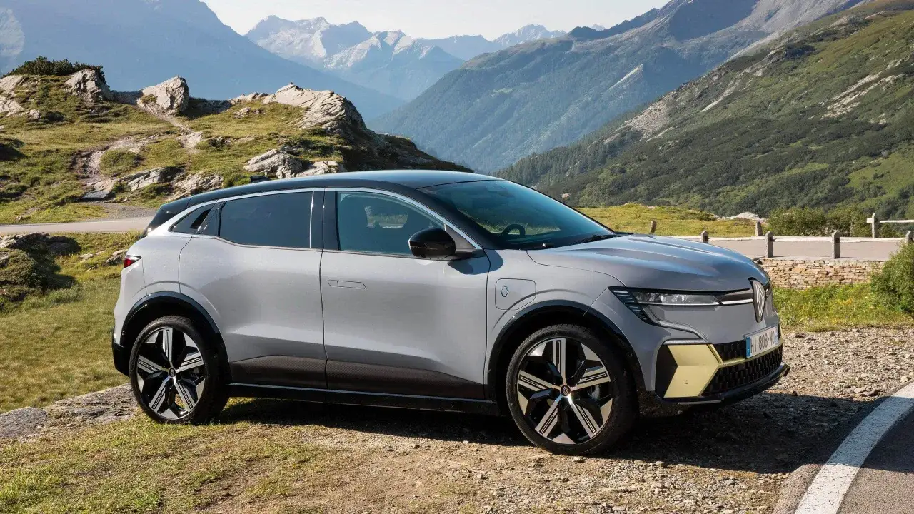 Grå Renault Megane E-Tech testbil parkerad i bergig terräng.