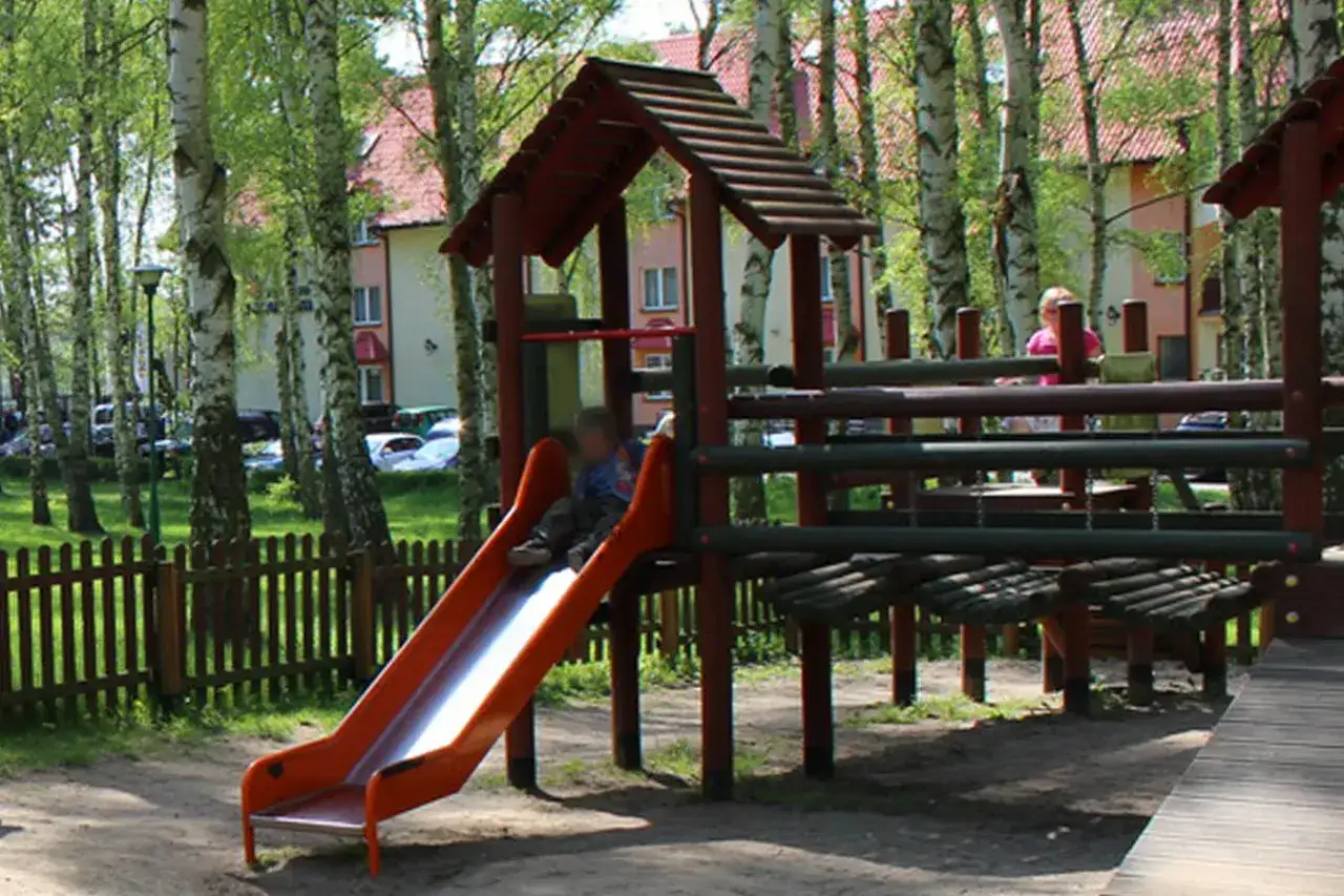 Dzieci bawią się na placu zabaw, zjeżdżalnia i drabinki to świetne atrakcje dla dzieci.