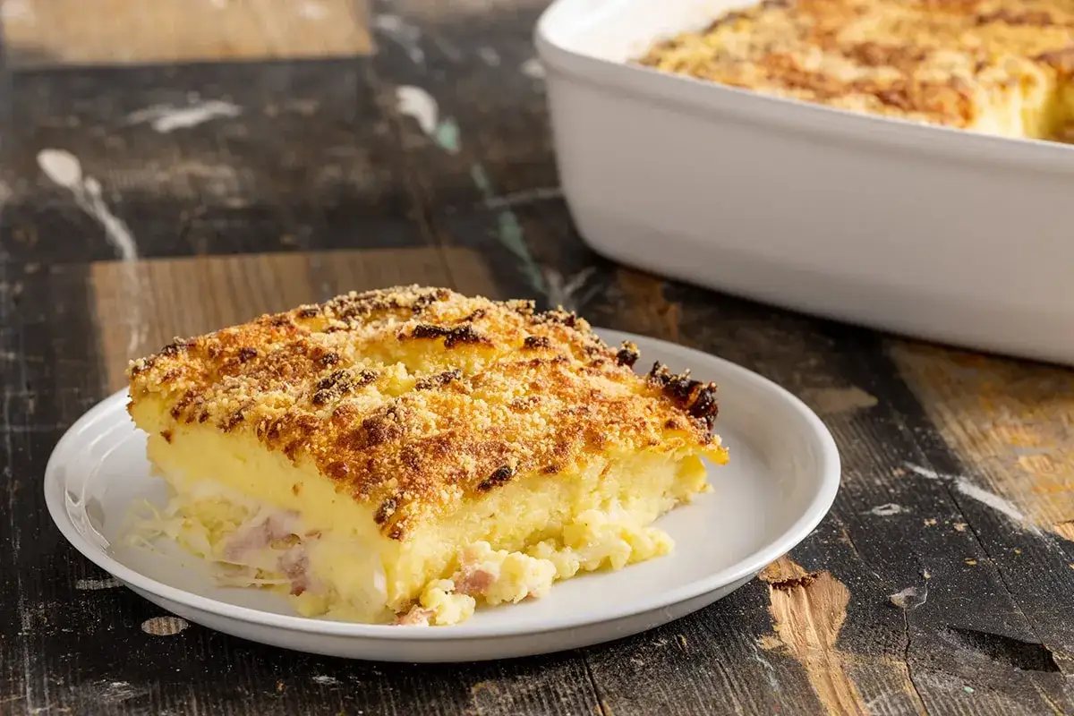 Una fetta di polpettone di patate dorato e croccante, con un ripieno filante, servita su un piatto bianco.