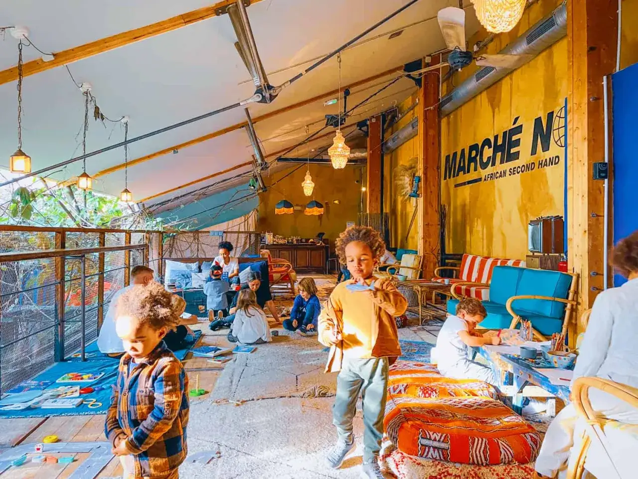 Enfants et adultes profitent d'un joyeux brunch en famille dans un espace lumineux et coloré, avec des jeux et des activités pour tous.