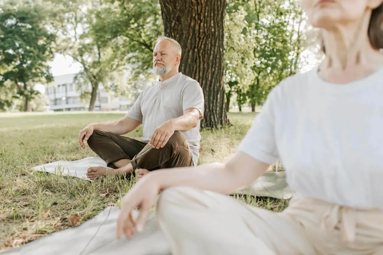 &Auml;ldre par mediterar i parken, en lugn stund f&ouml;r att bryta negativa tankar och finna inre frid.