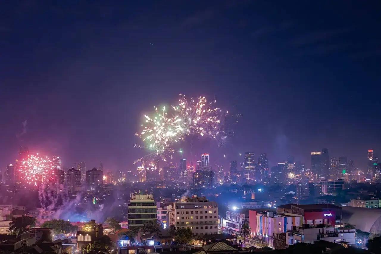 Un spectaculaire photo feu d'artifice illumine le ciel nocturne au-dessus d'une ville animée, ses gratte-ciel scintillants reflétant la magie des célébrations.