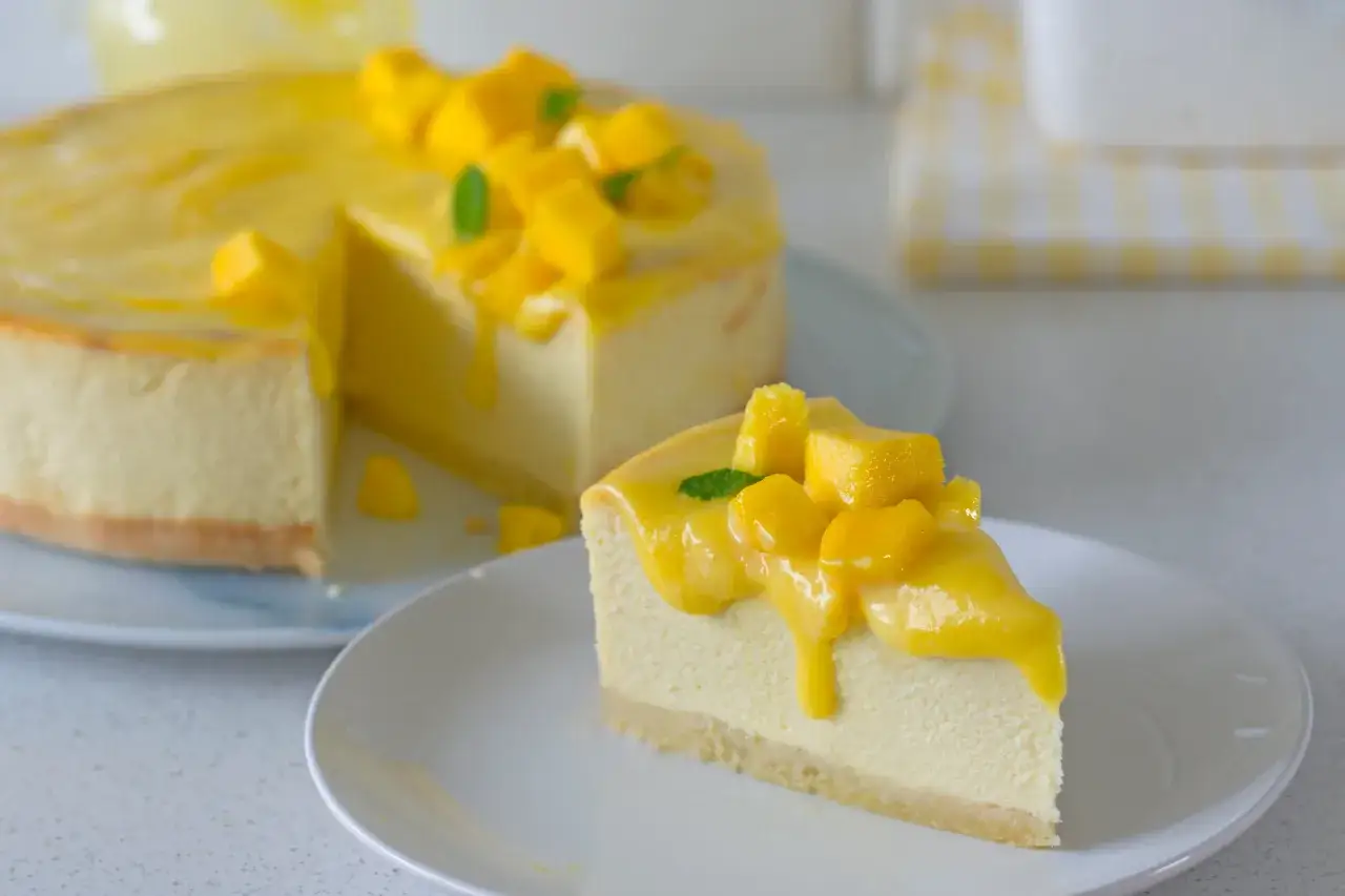 Pyszny sernik mango na zimno, udekorowany kawałkami mango i listkami mięty. Idealny na letnie popołudnie.