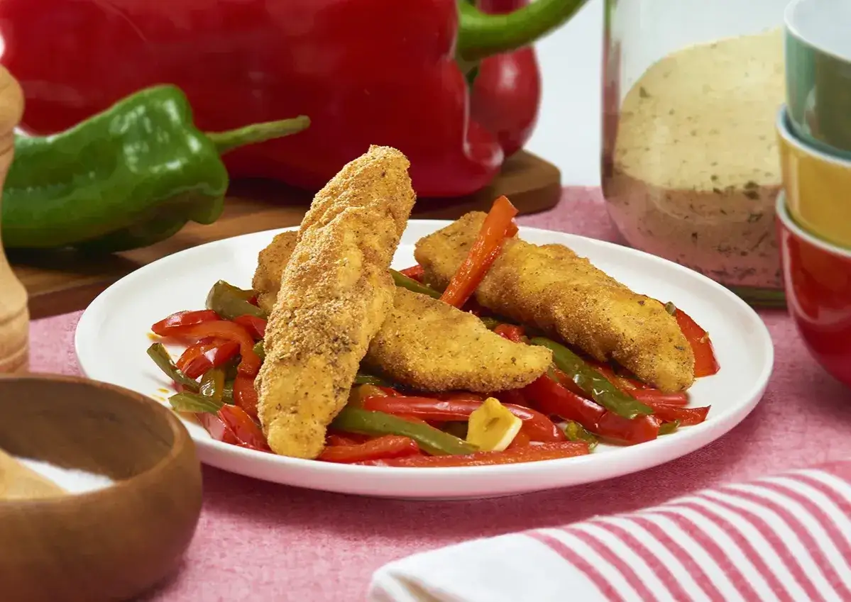 Crujientes tiras de pollo con pimientos rojos y verdes salteados, un plato colorido y sabroso.