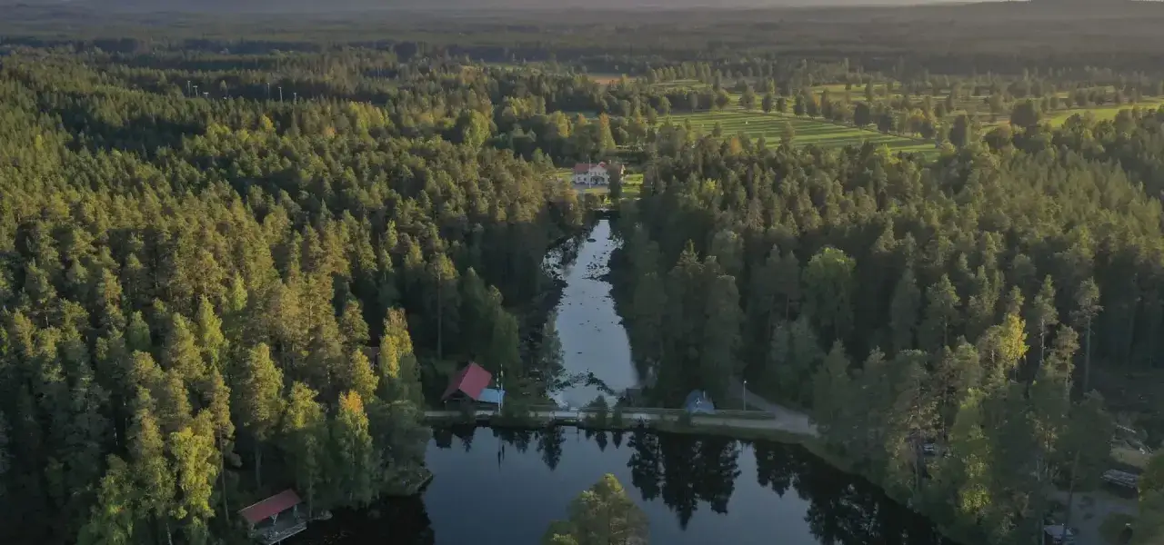 Vacker vy &ouml;ver skog och sj&ouml; med en herrg&aring;rd i bakgrunden. Ett perfekt utflyktsm&aring;l i Dalarna f&ouml;r natur&auml;lskare.