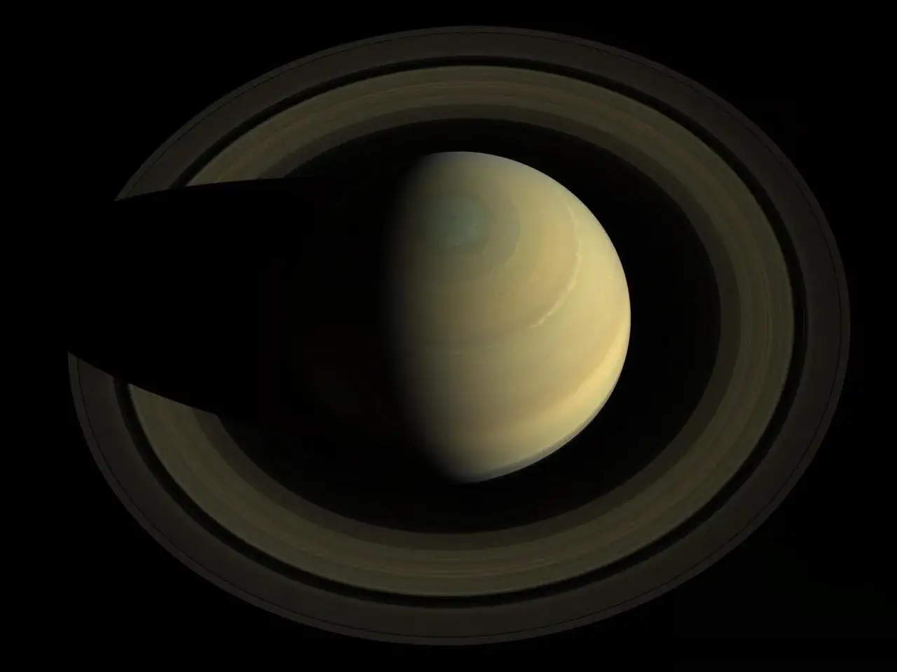 Saturn z pierścieniami, na kt&oacute;rego powierzchni widać wirującą burzę.