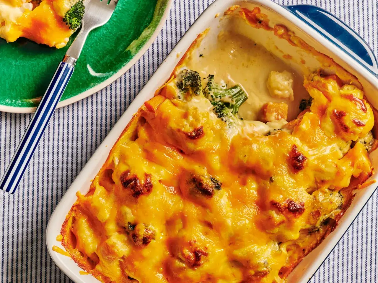Un plat de gratin de légumes au fromage fondant, avec du brocoli et des morceaux de patate douce, prêt à être dégusté.