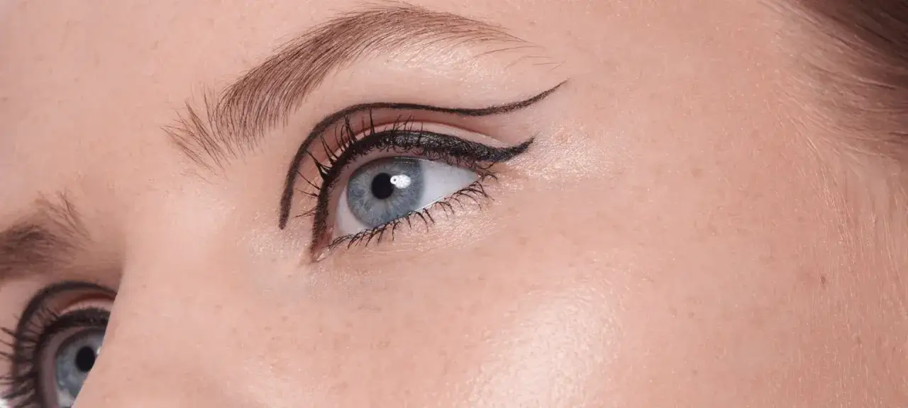 Occhio azzurro con un elegante eyeliner leggero che accentua la forma, ciglia lunghe e folte.