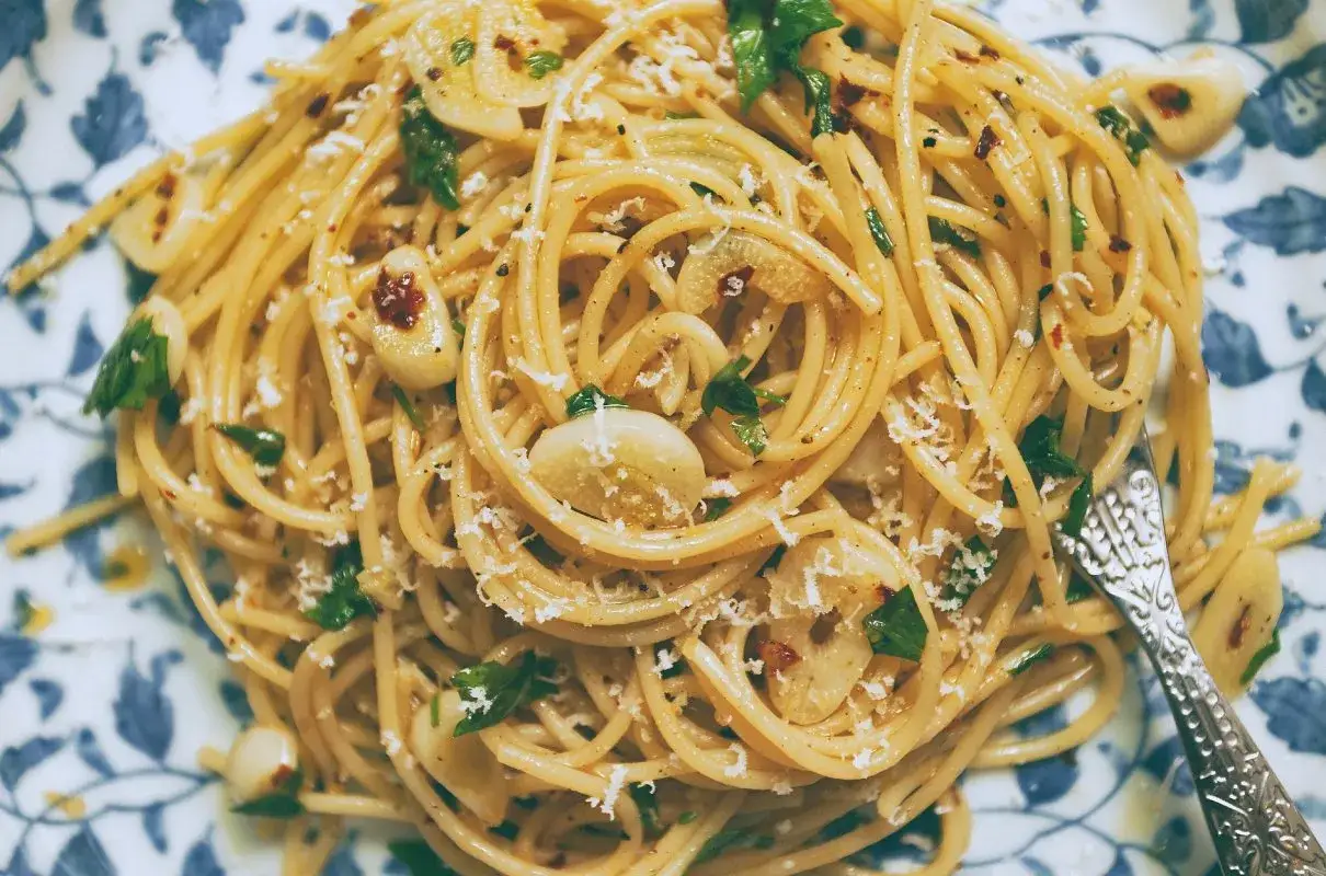 Pyszne spaghetti aglio olio z czosnkiem, natką pietruszki i płatkami chili, posypane parmezanem.