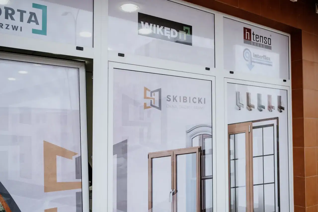 Witryna sklepowa z oknami i drzwiami, widoczne loga firm: Porta, Wikęd, H-tenso, Interflex, Skibicki.