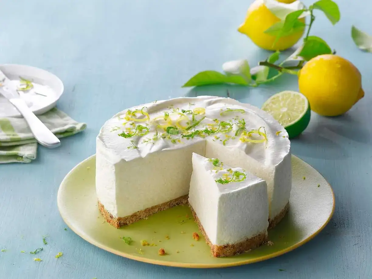 Kr&auml;mig cheesecake med frisk lemon curd, toppad med rivet citronskal. En bit &auml;r uppskuren.