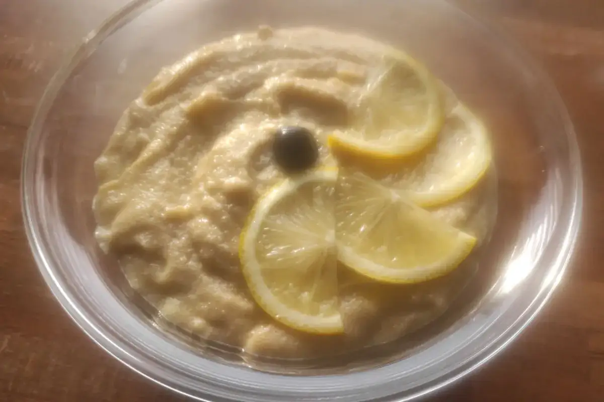 Un délicieux tarama maison, crémeux et onctueux, garni de fines rondelles de citron et d'une olive noire.