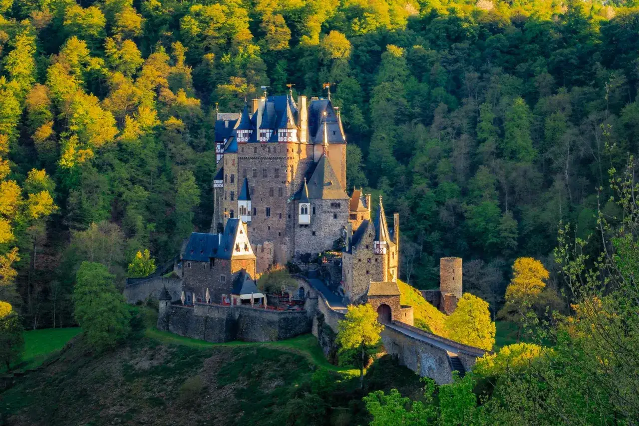 Burg Eltz, ein m&auml;rchenhaftes Schloss, ist ein Muss f&uuml;r ausflugsziele rheinland pfalz. Umgeben von &uuml;ppigen W&auml;ldern, strahlt es im warmen Abendlicht.
