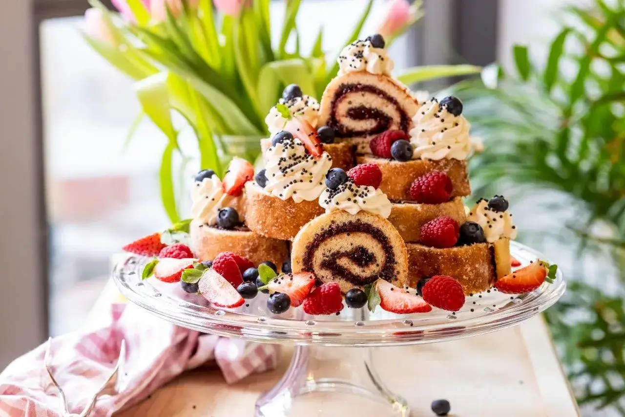 En imponerande rulltårta som tårta, dekorerad med grädde, bär och strössel. En festlig dessert!