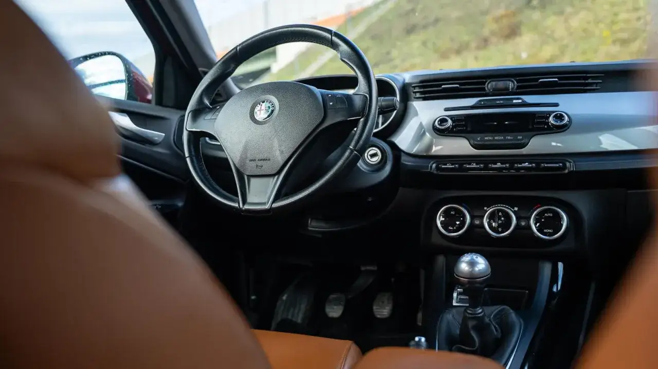 Wnętrze Alfa Romeo Giulietta. Kierownica, deska rozdzielcza i dźwignia zmiany biegów. Wiele osób chwali ten model, a alfa romeo giulietta opinie są pozytywne.