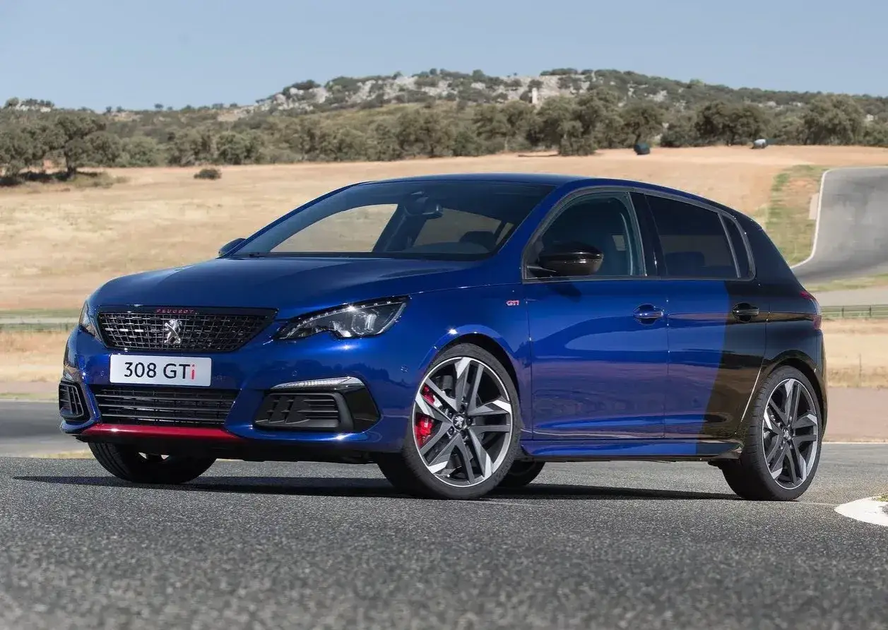 Niebieski Peugeot 308 GTi z czerwonymi zaciskami hamulcowymi na torze wyścigowym.