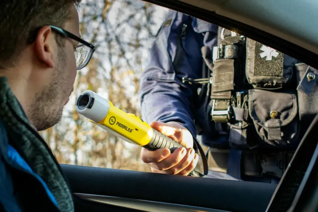 Policjant podaje kierowcy alkomat. To miejsce, gdzie można zbadać się alkomatem, by upewnić się, że jazda jest bezpieczna.