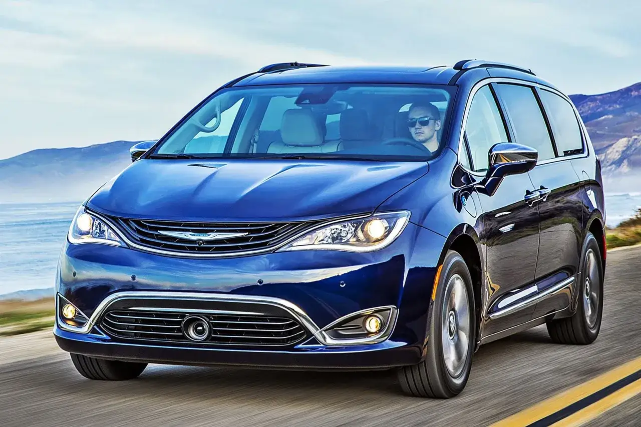 Niebieski Chrysler Pacifica jedzie nad oceanem. Kierowca w okularach przeciwsłonecznych. Sprawdź chrysler pacifica spalanie.
