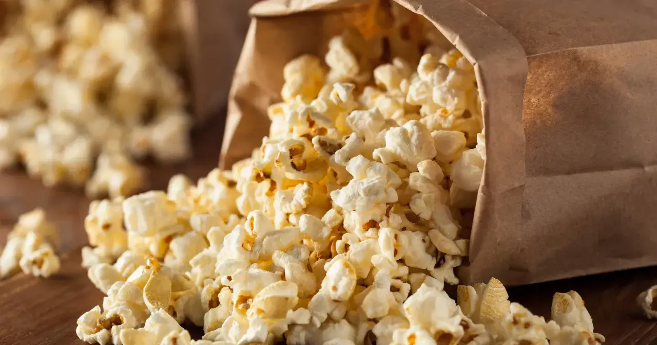 Góra brązowej torby z wysypującym się popcornem. Idealna przekąska, ale warto pamiętać o popcorn kcal.
