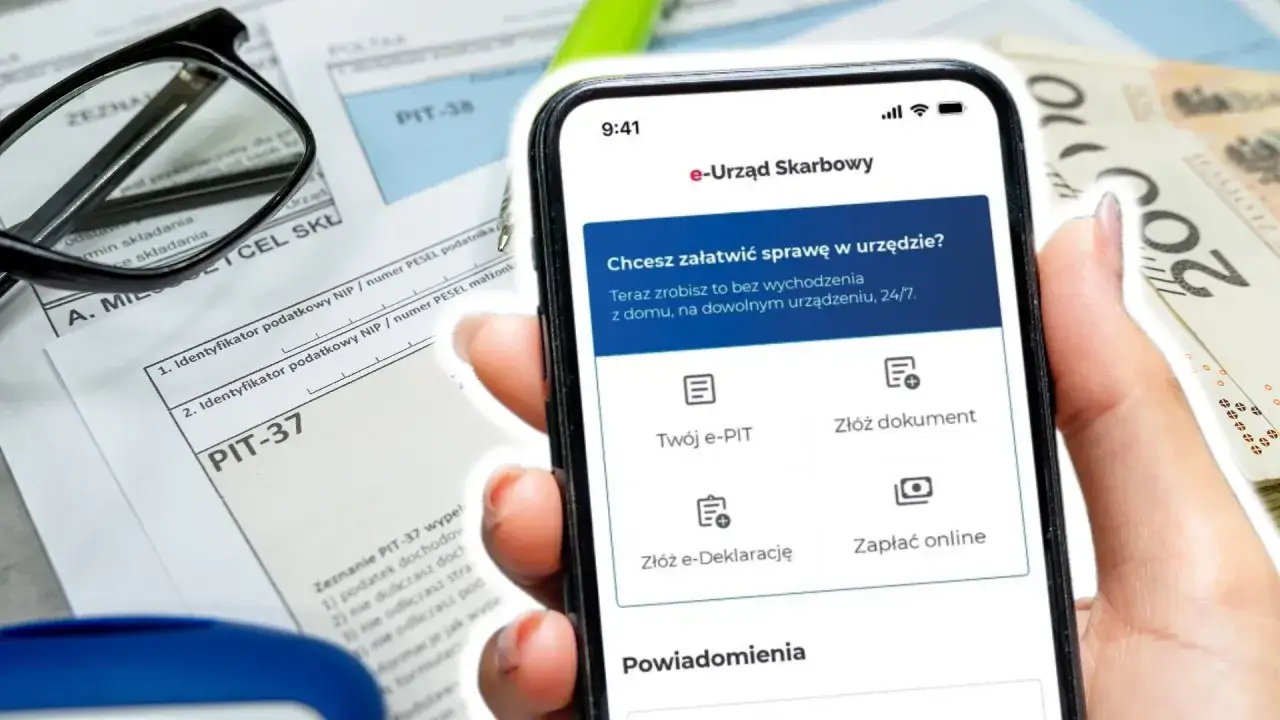 Dłoń trzyma smartfon z aplikacją e-Urząd Skarbowy, obok formularze PIT i pieniądze. Można tu złożyć PIT-37, PIT-38 i inne dokumenty.