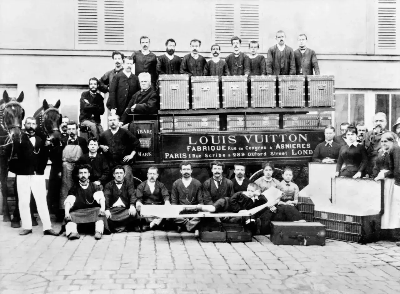 Gruppo di persone con bauli Louis Vuitton, che indica