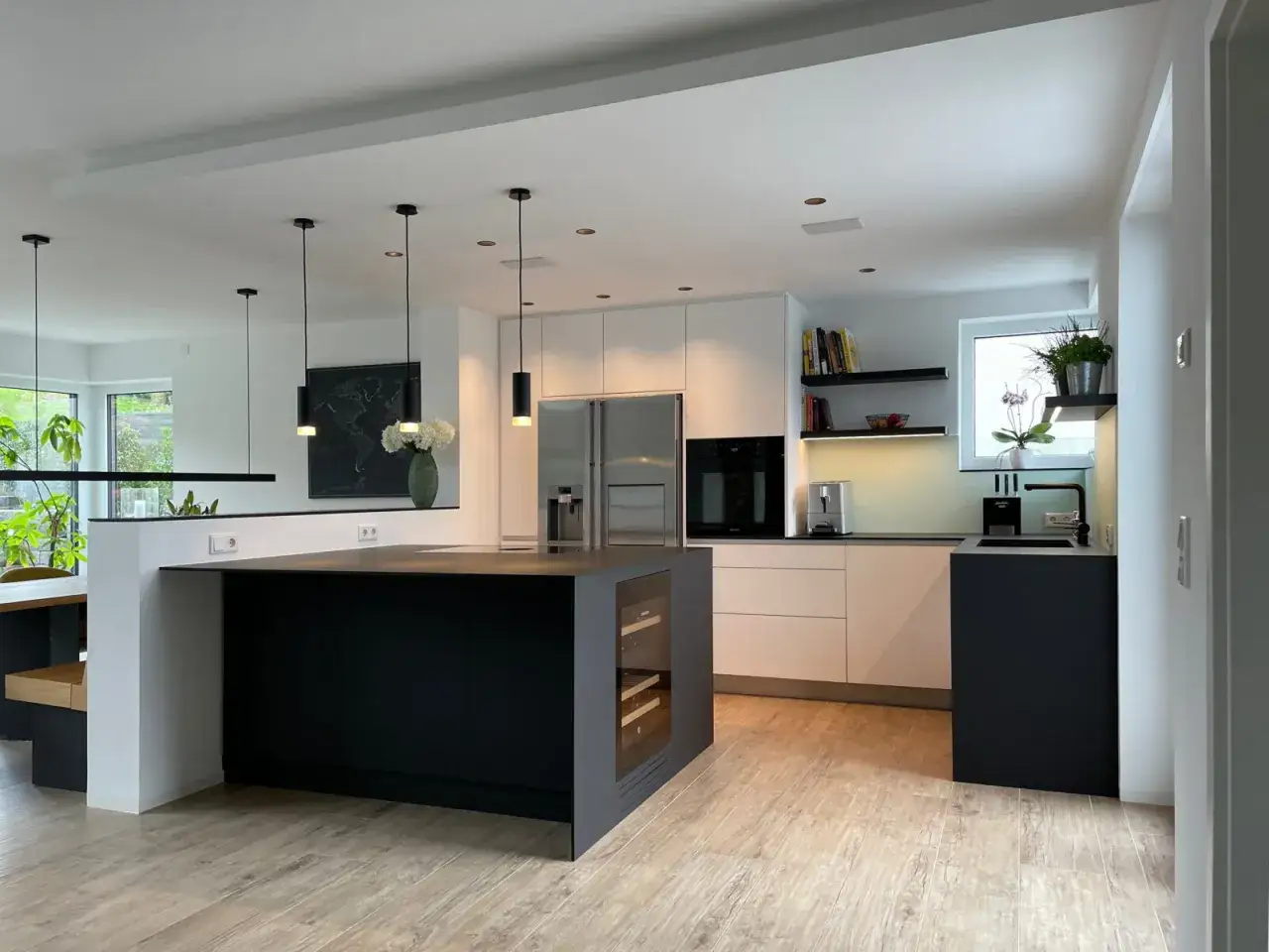 Moderne Küche mit schwarzer Kochinsel und integriertem Weinkühler, ideal, um die Essecke modern gestalten.
