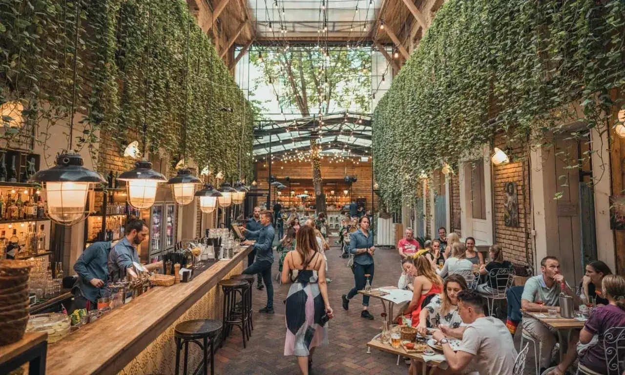 Grüner Innenhof mit vielen Pflanzen, Bar und Tischen. Ein toller Ort für Budapest Geheimtipps.