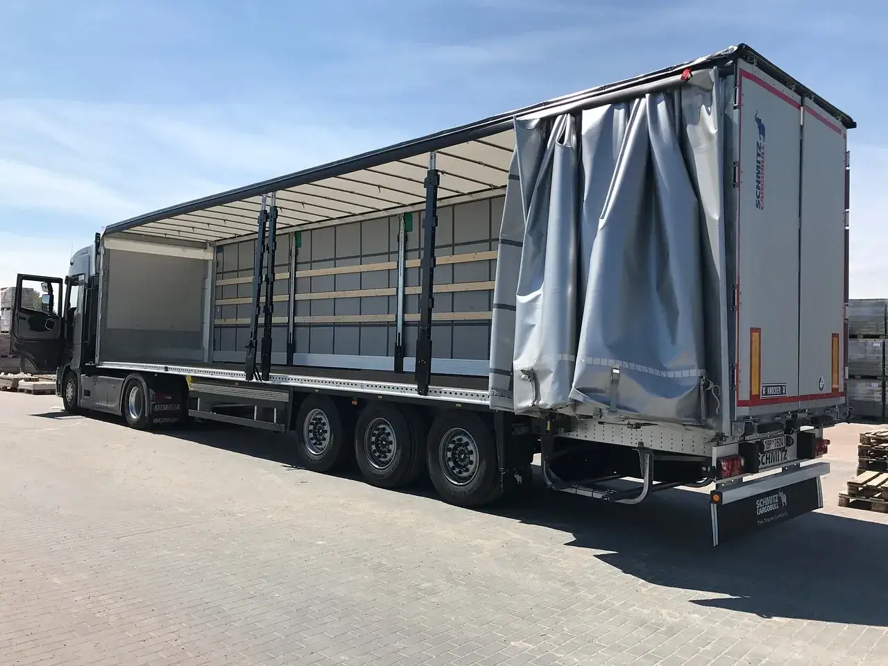 Ciężarówka z naczepą typu firanka, gotowa do załadunku. Spedytor, kto to? To osoba organizująca transport.