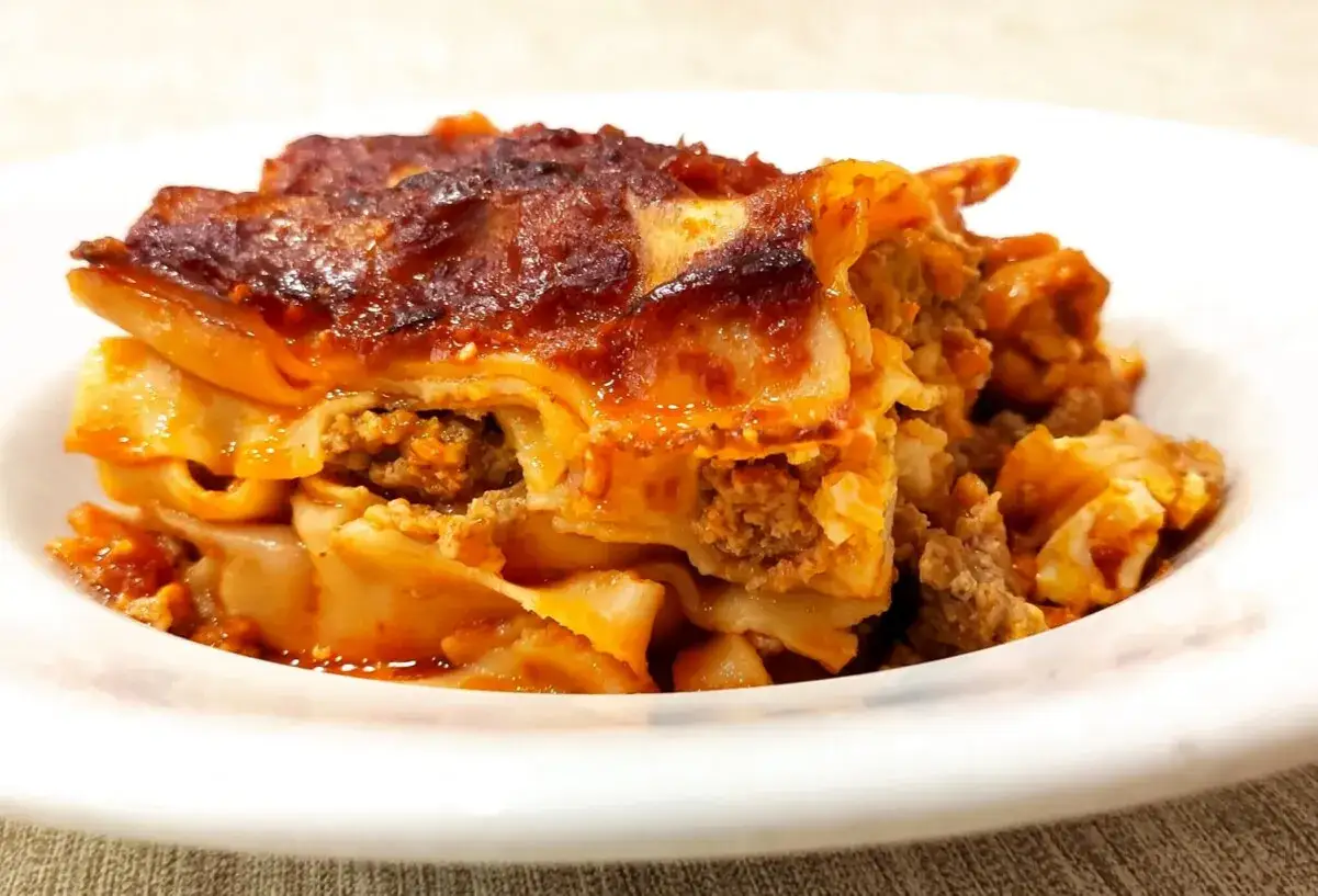 Porzione di lasagna al ragù, uno dei piatti tipici di Avellino, servita su un piatto bianco.