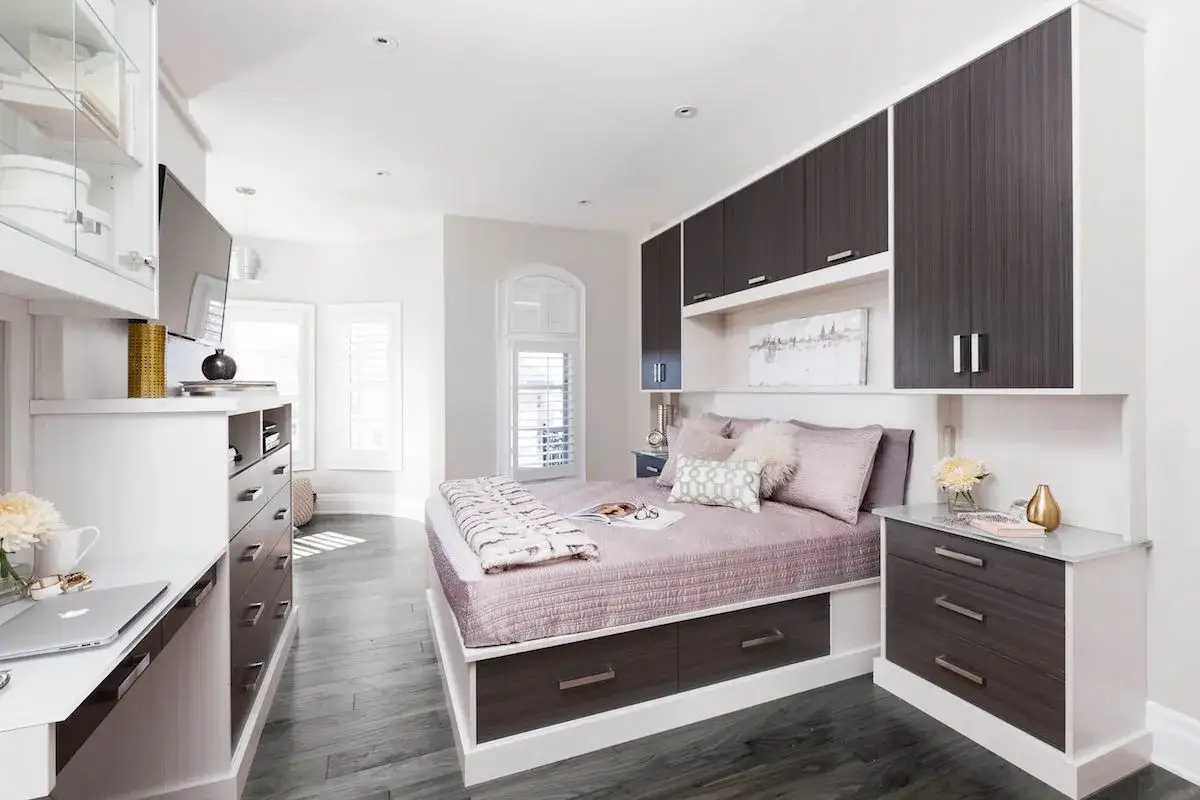 Habitación moderna con cama, escritorio y armarios empotrados. Todo organizado para optimizar el espacio, ideal para organizar canapé y tener todo a mano.