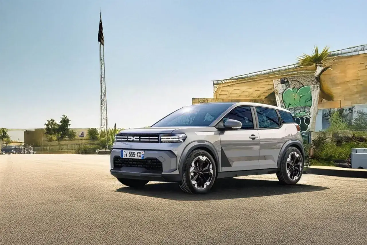 Nowy samochód Dacia stoi na tle miejskiego krajobrazu z graffiti.