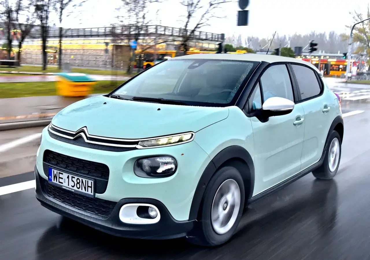 Jasny, francuski samochód Citroën C3 jedzie po mokrej drodze.