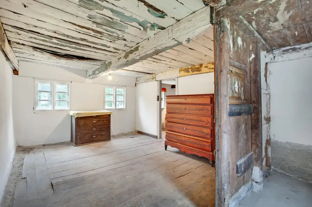 Ett rum i ett hus fr&aring;n 1700-talet med slitna tr&auml;golv, takbj&auml;lkar och tv&aring; gamla byr&aring;er.