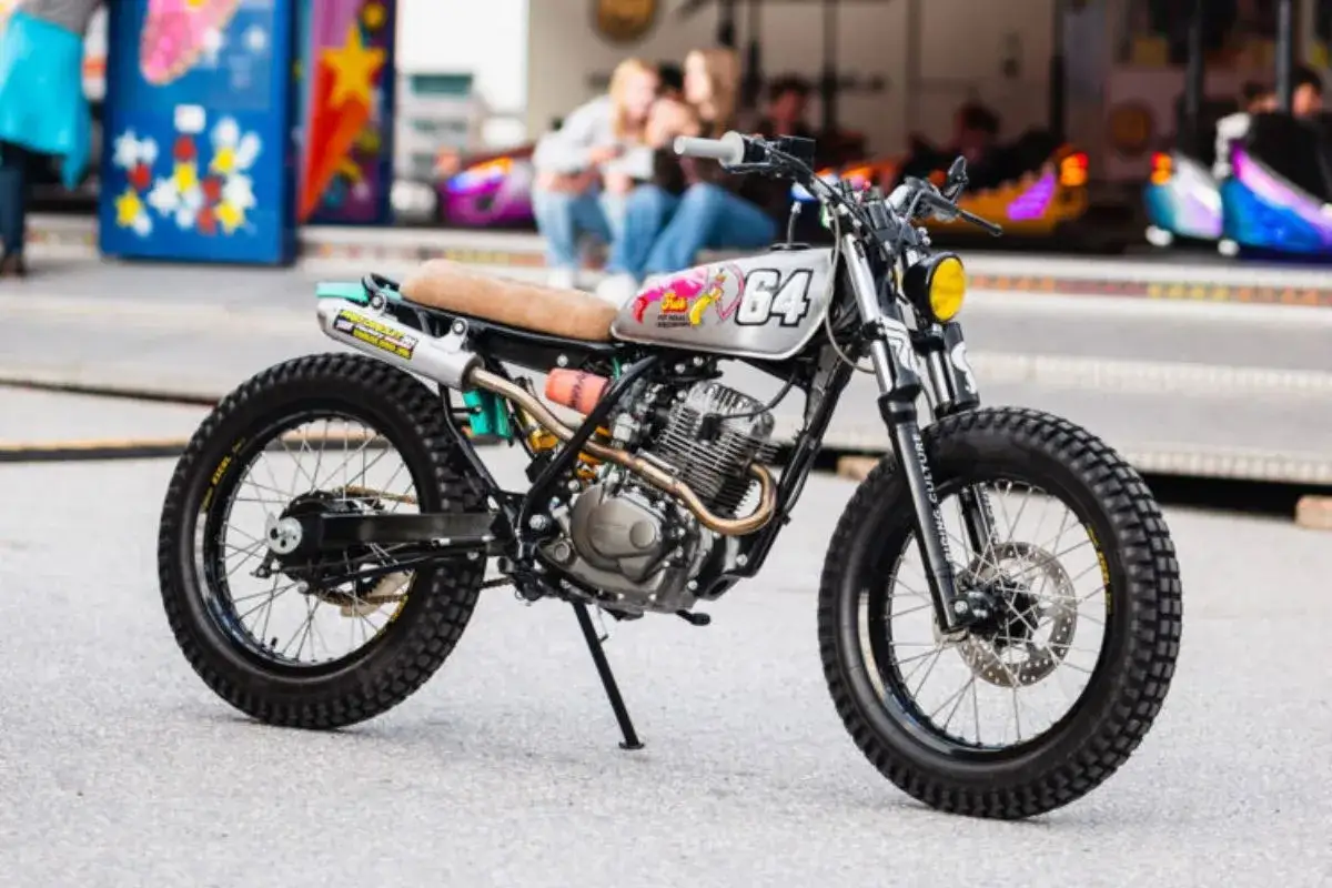 Honda scrambler 750 personalizada con detalles retro y n&uacute;mero 64 en el tanque. Ruedas todoterreno y escape modificado.