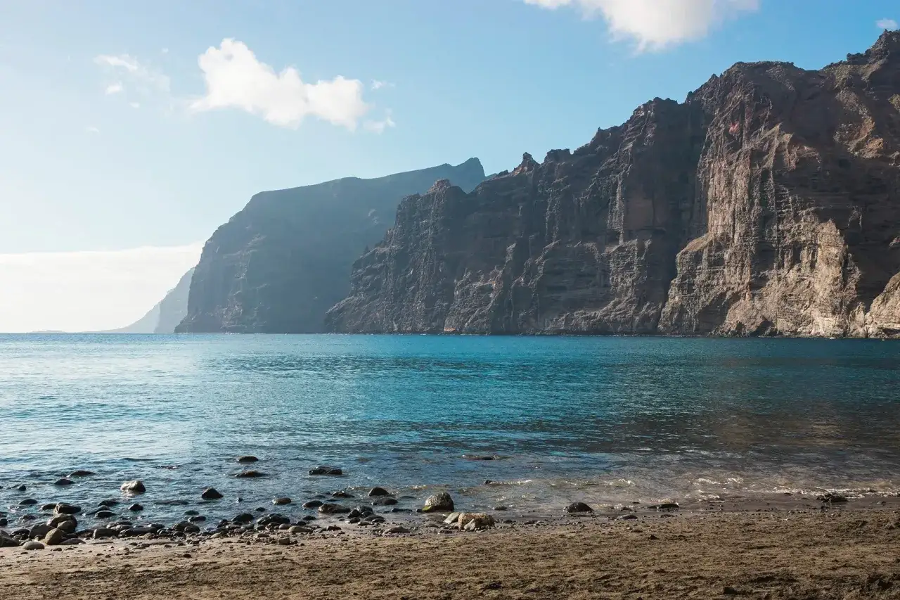 Vue sur les falaises de Los Gigantes, des géants de roche plongeant dans l'océan bleu turquoise. La plage de galets invite à la contemplation.