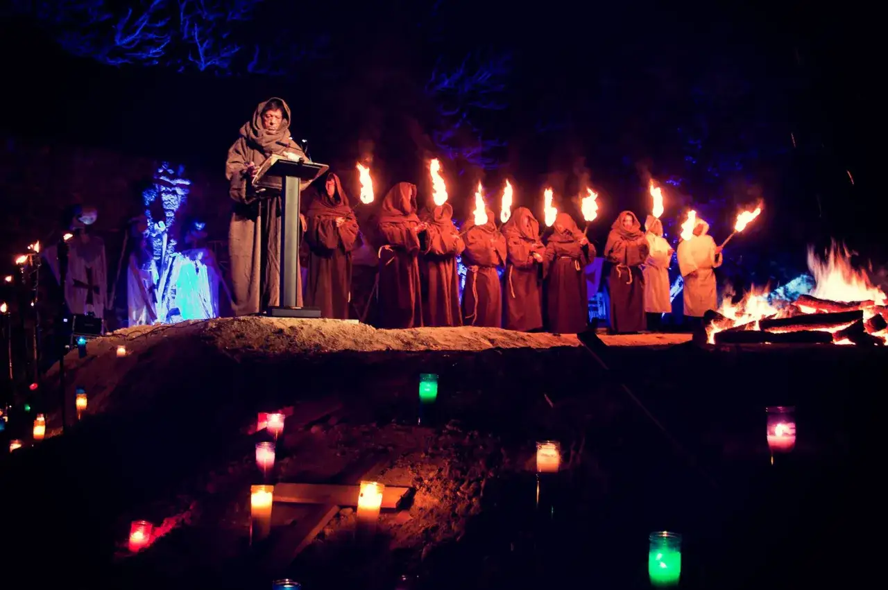 Un grupo de monjes con t&uacute;nicas y antorchas ilumina la noche, evocando el ambiente de 