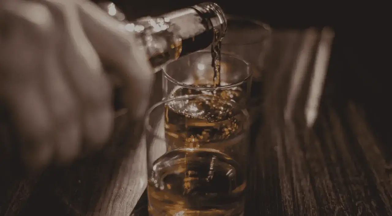 En hand häller upp alkohol i glas. För vissa med adhd kan alkohol vara en risk.