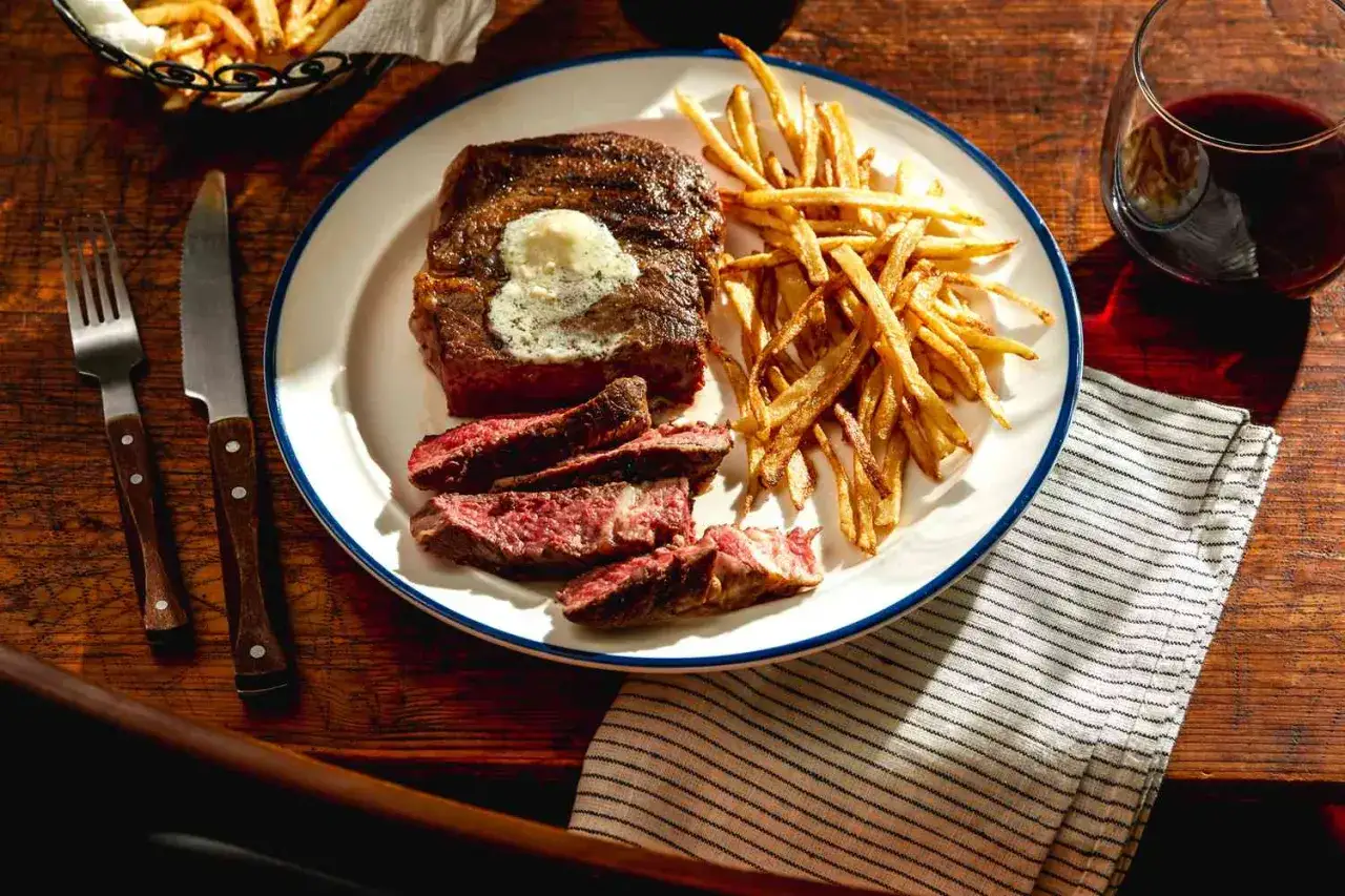 En tallrik med saftig steak frites, perfekt stekt kött med smält smör och gyllene pommes frites. En klassisk måltid.