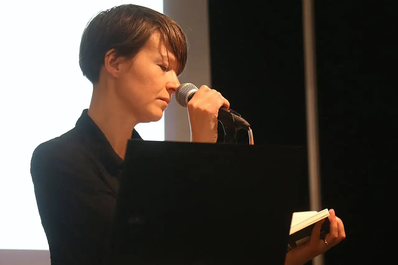 Jenny Tunedal håller en mikrofon och en bok, redo att dela sina ord.