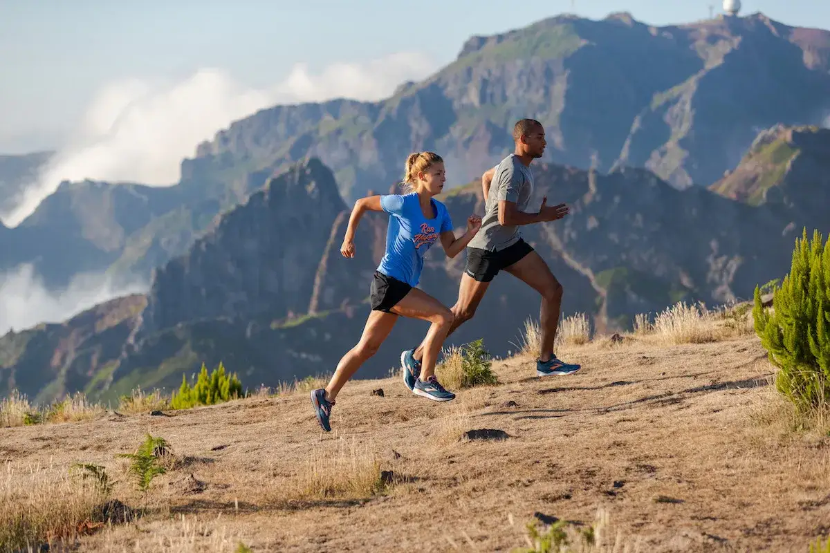 Un couple court dans un paysage montagneux, profitant de leur séance de sport pour courir 20 minutes par jour.