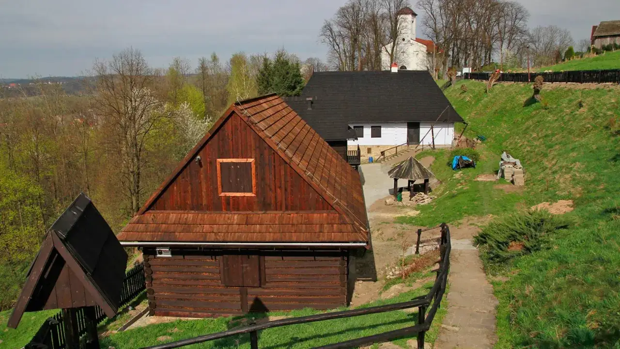 Skansen w Dobczycach zaprasza do drewnianych chat i białego kościółka. Wiosenna zieleń otula malowniczy krajobraz.