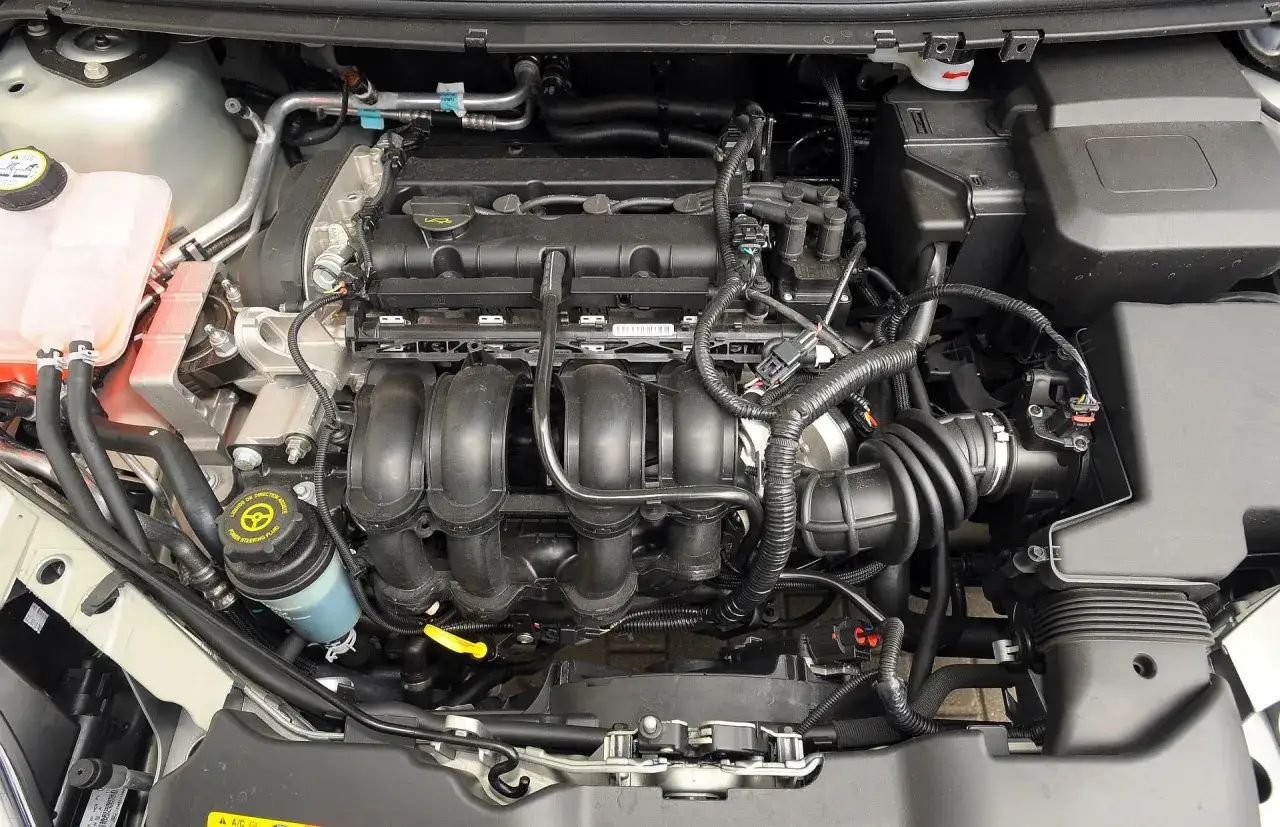 Silnik Ford Focus MK2, czarny kolektor dolotowy, zbiornik płynu chłodniczego i przewody.