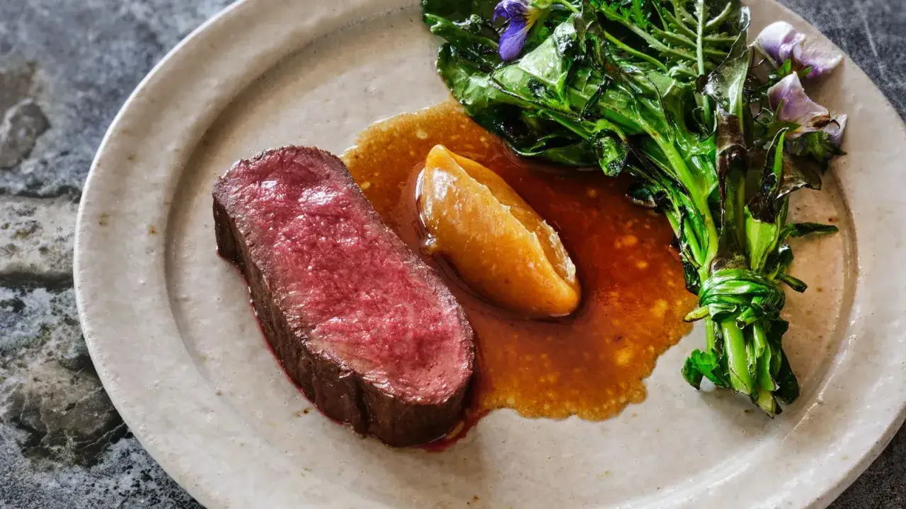 En saftig biff med en gyllene äppelkompott och gröna blad, inspirerad av klassiska fransyska recept.
