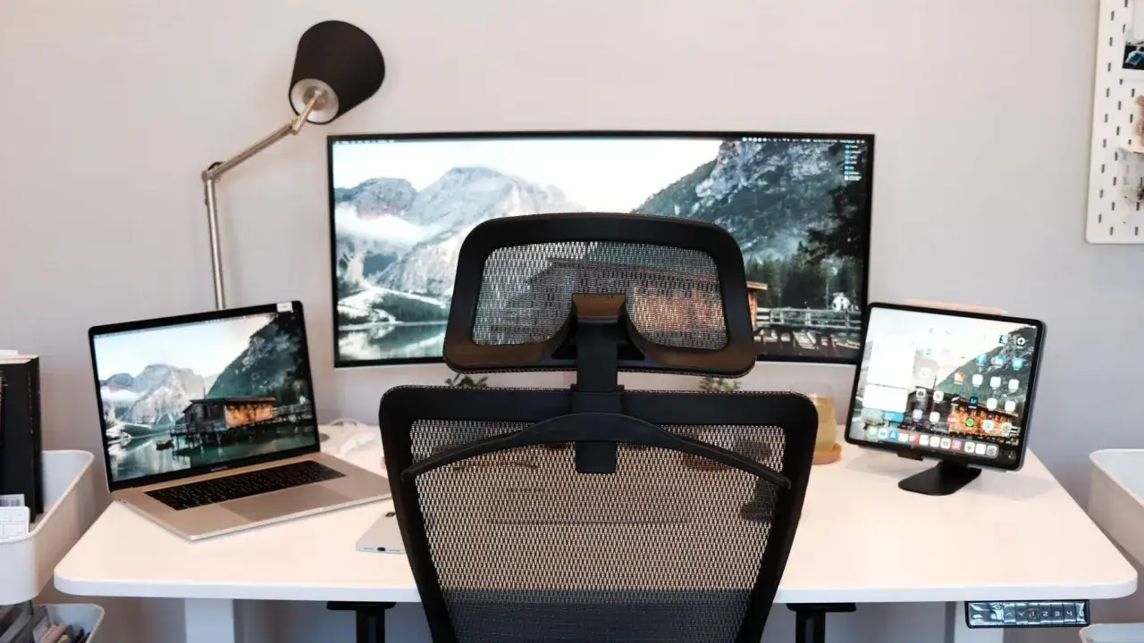 Un bureau moderne avec un ordinateur portable, un grand écran et une tablette, parfait pour un setup développeur.