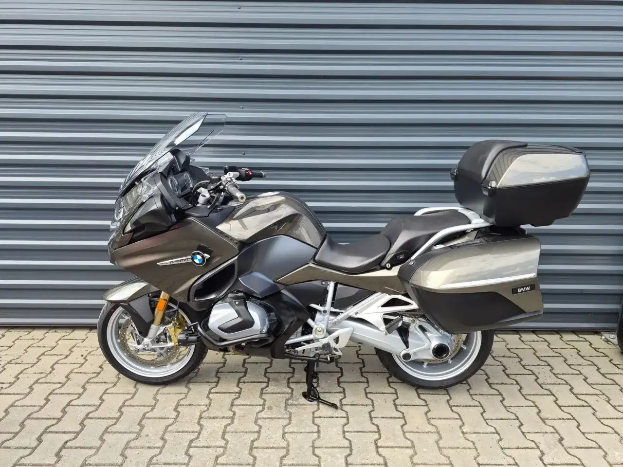 Brązowy motocykl turystyczny BMW R 1250 RT z kuframi, gotowy na dalekie podróże.
