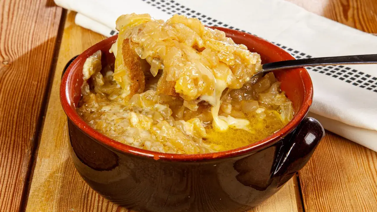 Una ciotola fumante di zuppa di cipolle toscana, con crostini dorati e formaggio filante, pronta per essere gustata.