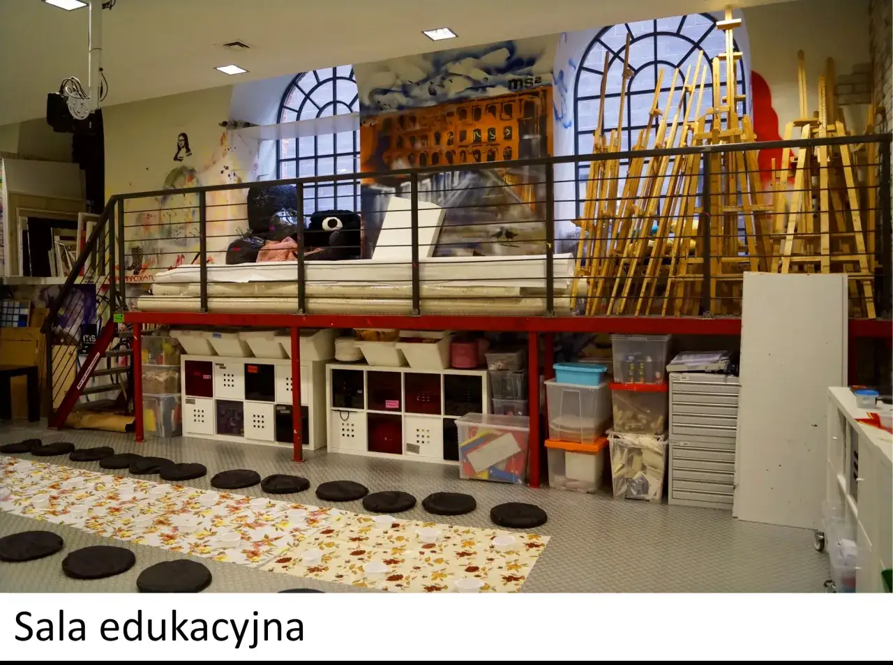 Sala edukacyjna w łodzi muzeum sztuki współczesnej ms2. Wnętrze pracowni z materacami, sztalugami i pojemnikami na materiały.