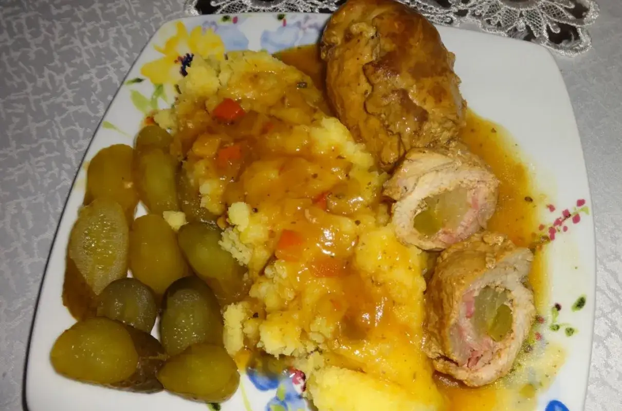 Zraz wieprzowy z ziemniakami i ogórkami kiszonymi, polany sosem.