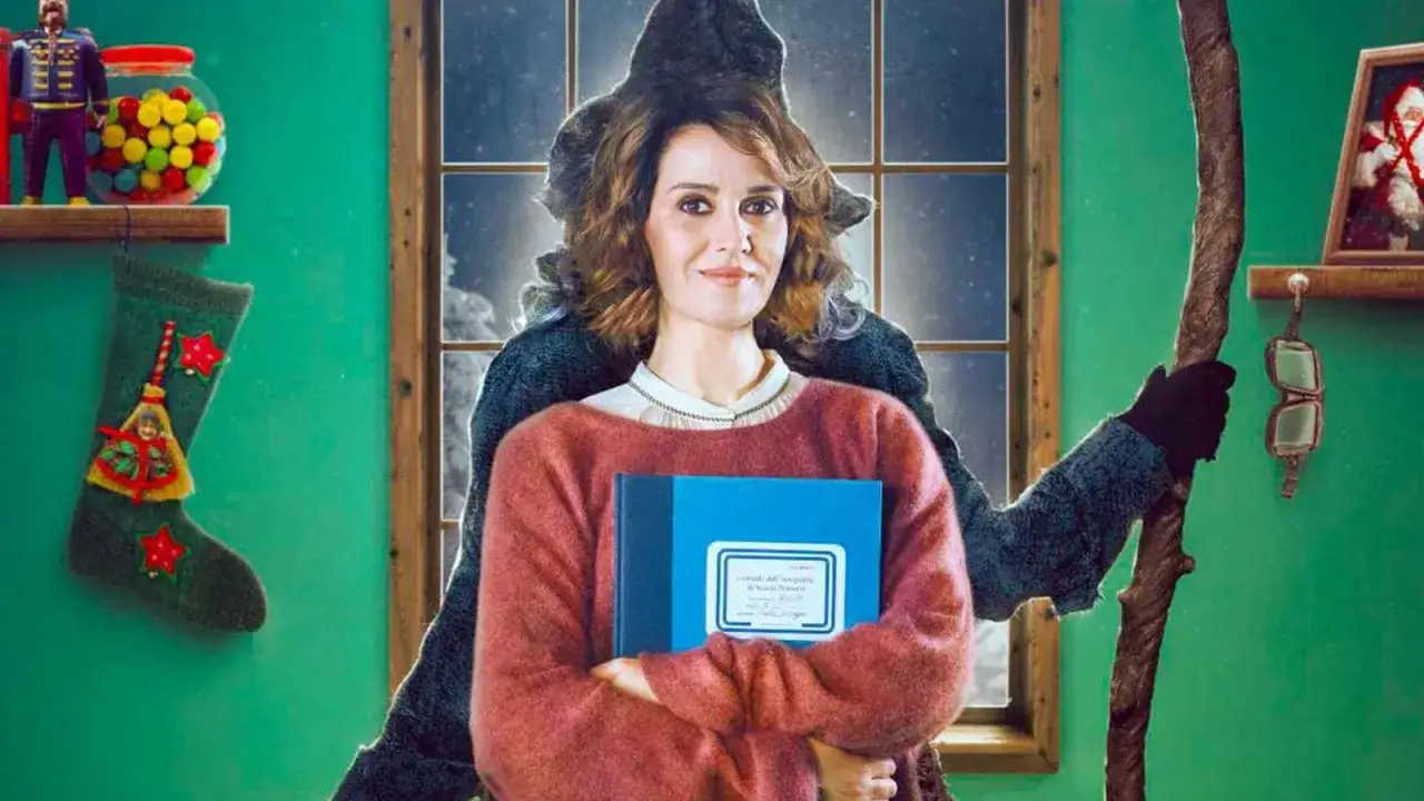 La Befana vien di notte, con un libro blu in mano, dietro di lei un'ombra misteriosa. Calza, caramelle e un quadro di Babbo Natale completano la scena.