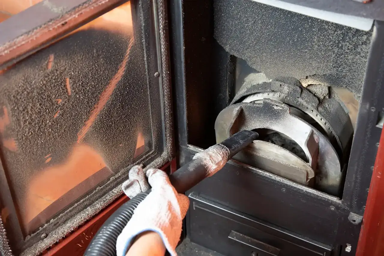 Mano con guanto bianco aspira cenere e residui dalla stufa a pellet, pulizia essenziale per il suo corretto funzionamento.